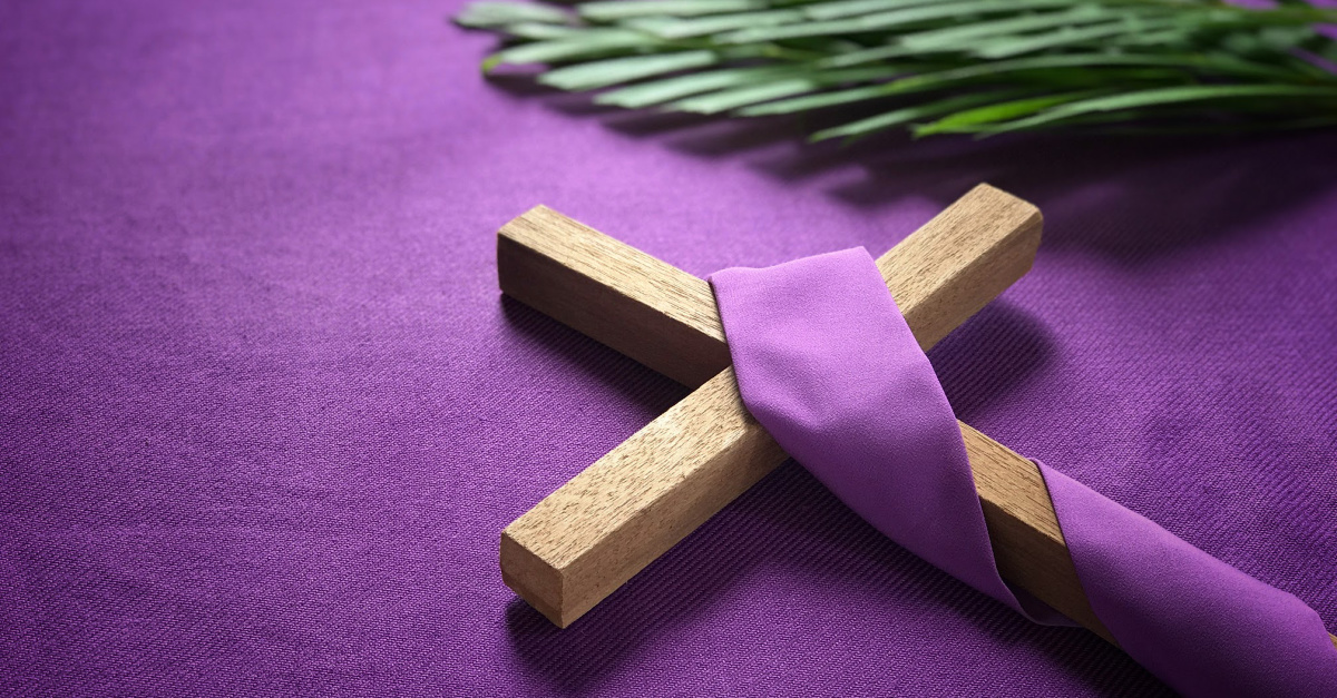 A religious cross and palm leaves on purple background.
